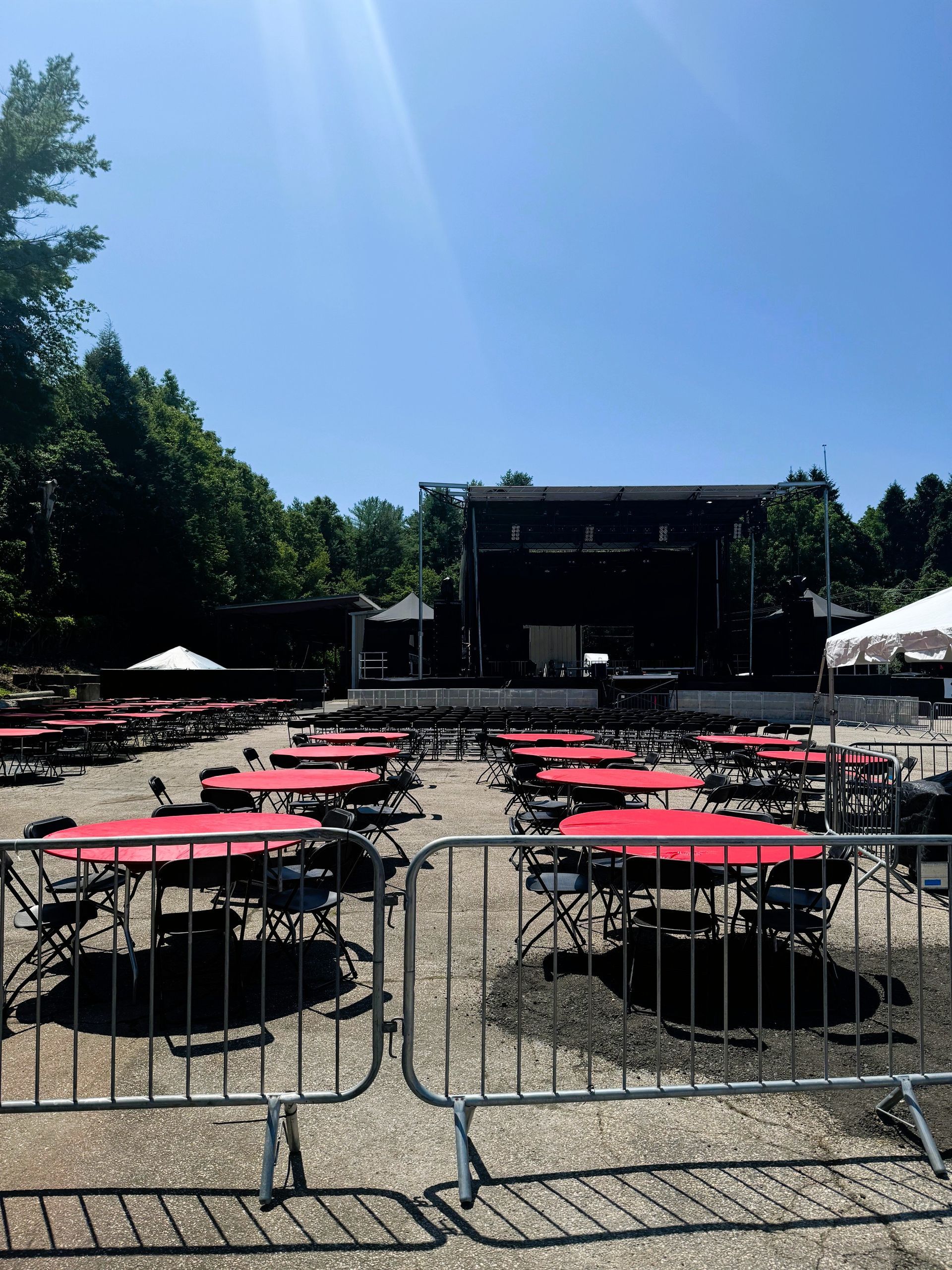 A lot of red tables and chairs are lined up in front of a stage.