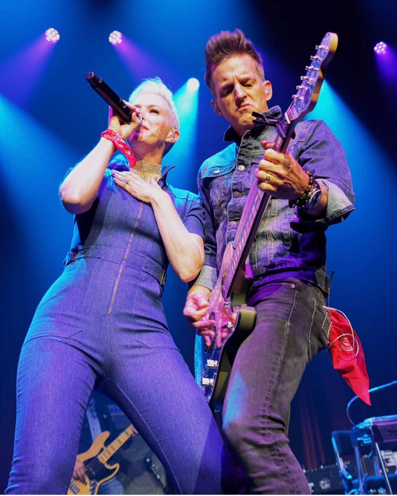 A man playing a guitar next to a woman singing into a microphone