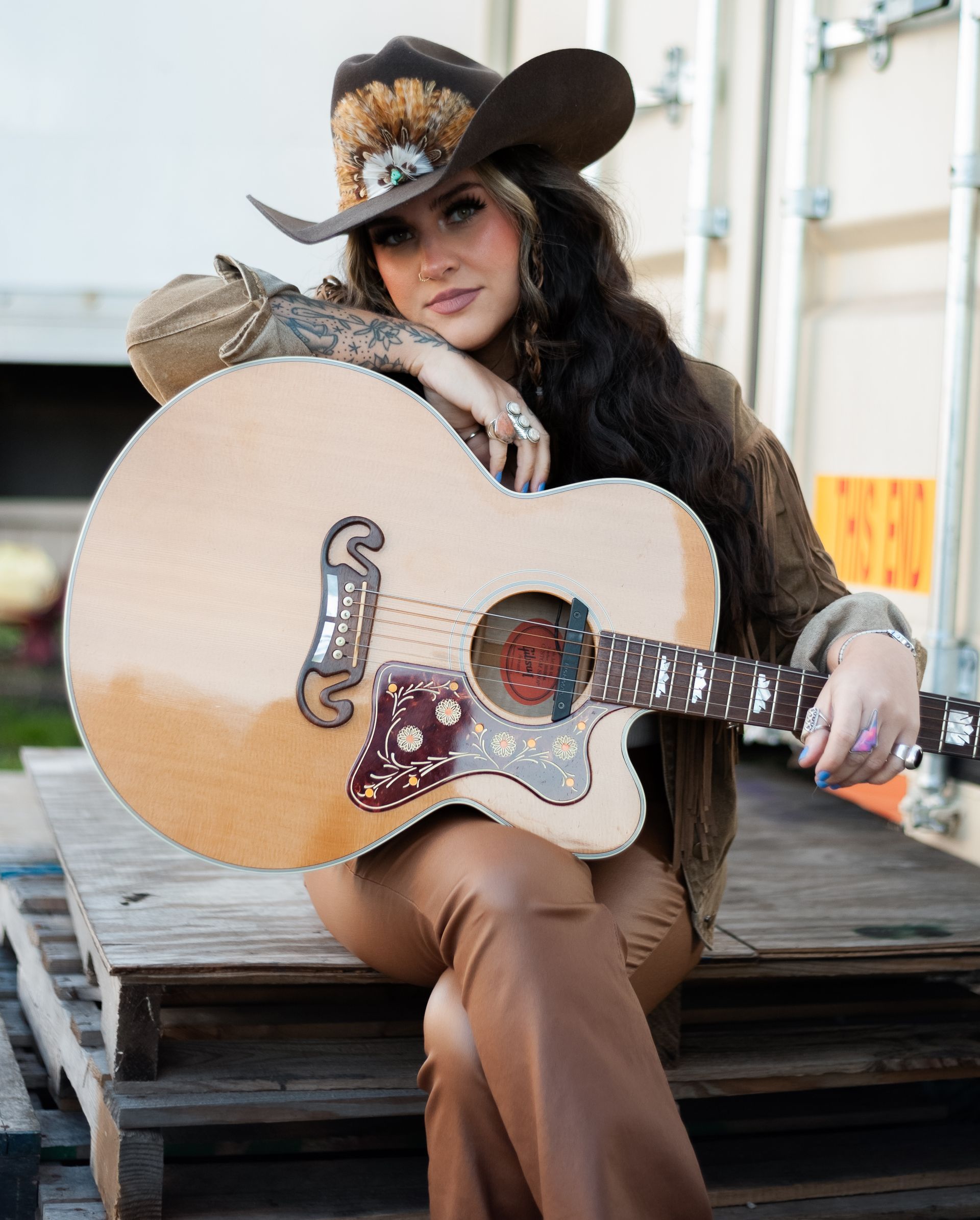 A woman in a cowboy hat is holding a guitar.