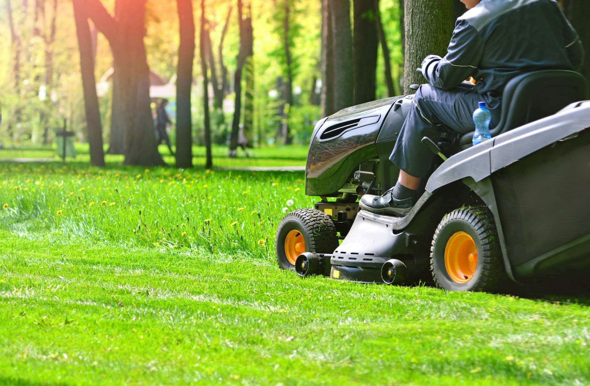 A man is riding a lawn mower in a park.