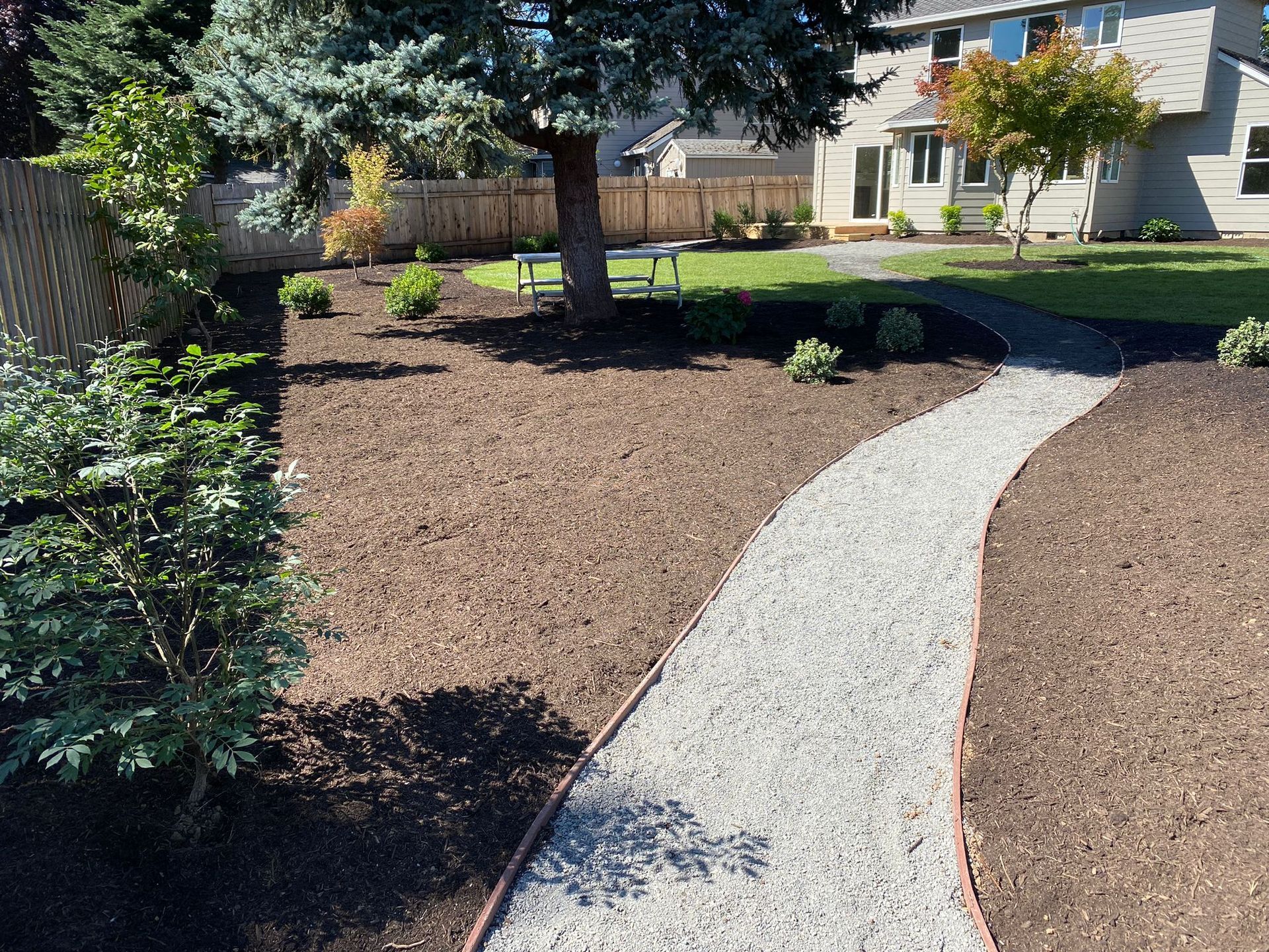 A gravel path leading to a house in a backyard.