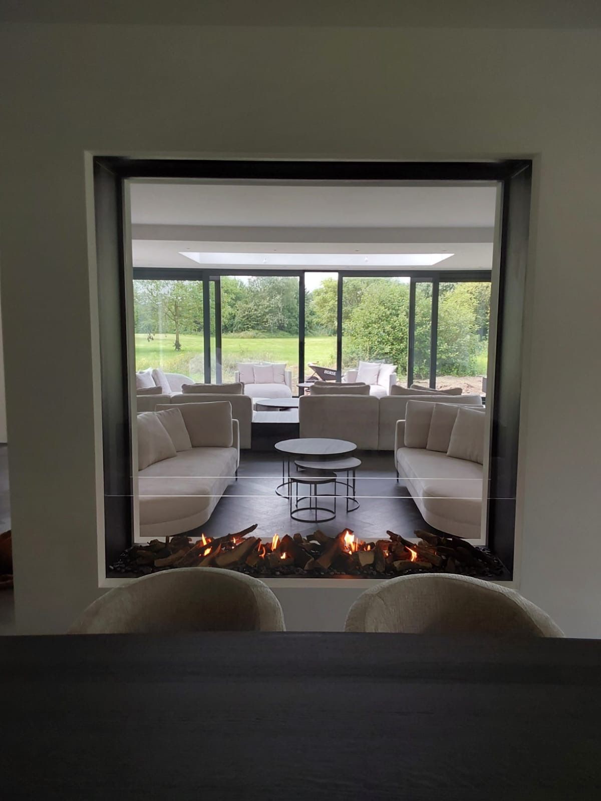 Een woonkamer met open haard en veel ramen