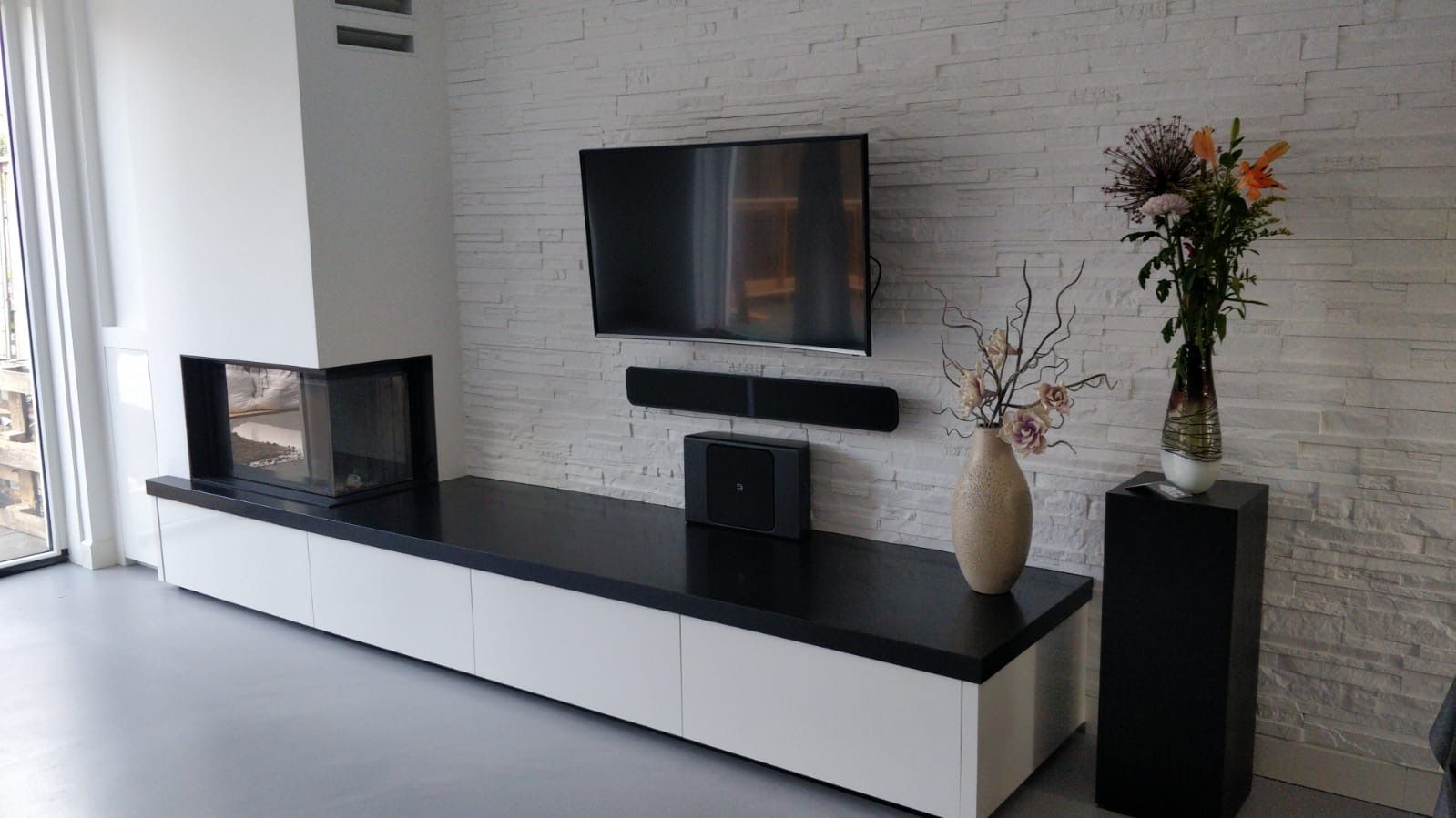 Een woonkamer met een open haard en een flatscreen-tv aan de muur.