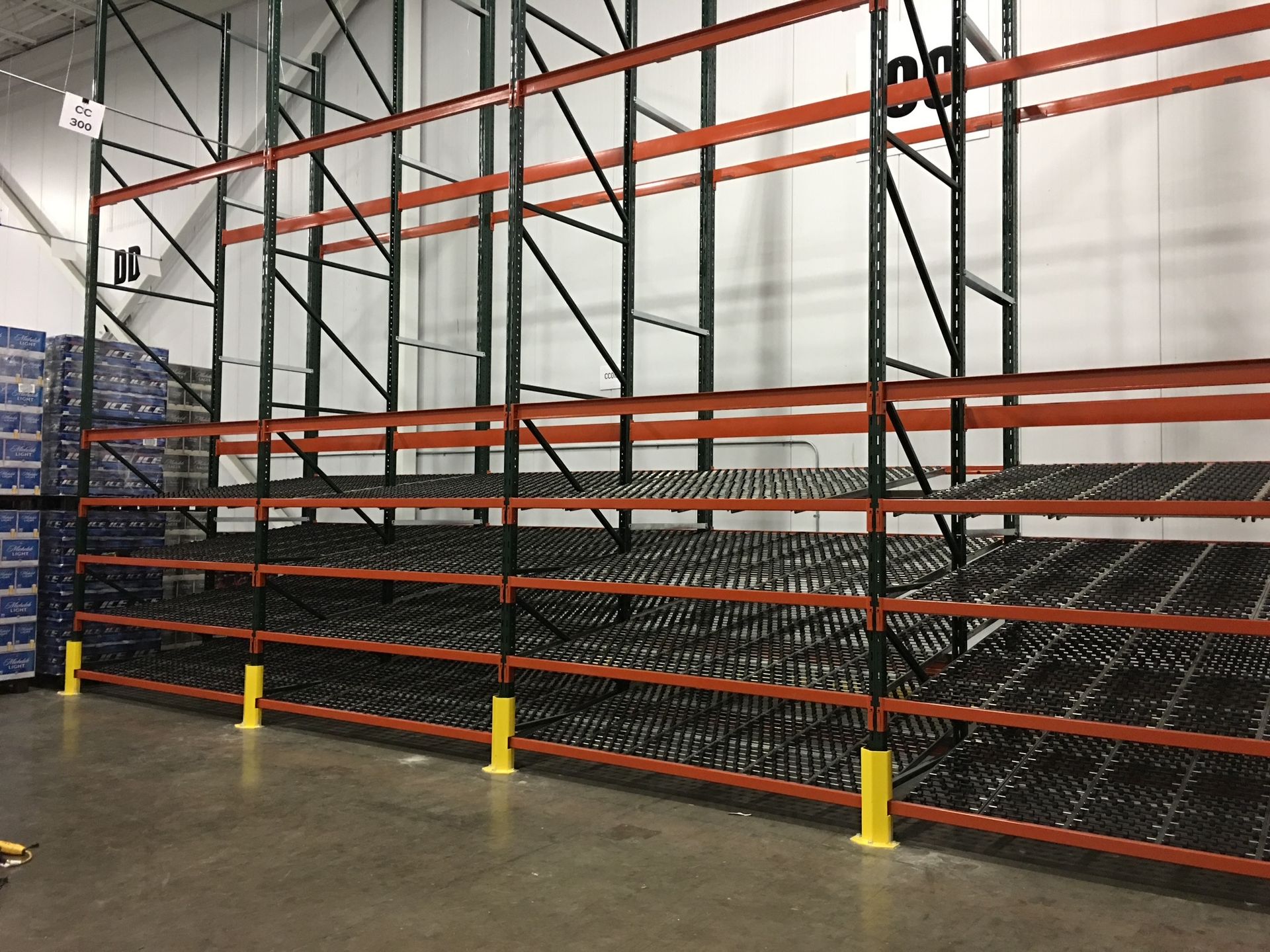 Warehouse shelving with rollers, orange and green, for storing items, with some items stored.