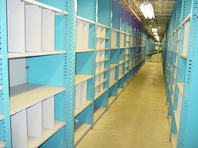 Blue shelves in a narrow aisle, empty and ready for storage in a warehouse or similar setting.
