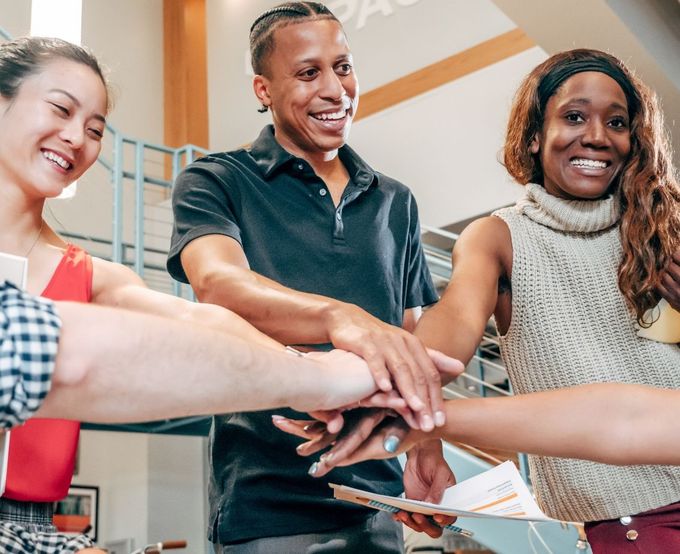 A group of people are putting their hands together in a huddle.