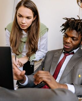 A man and a woman are looking at a laptop computer.