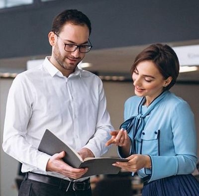 A man and a woman are looking at a book together.