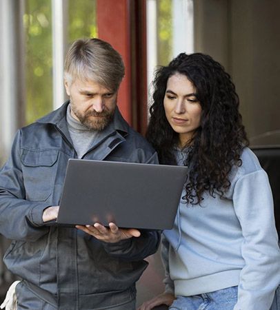 A man is shaking hands with a woman in front of a window.