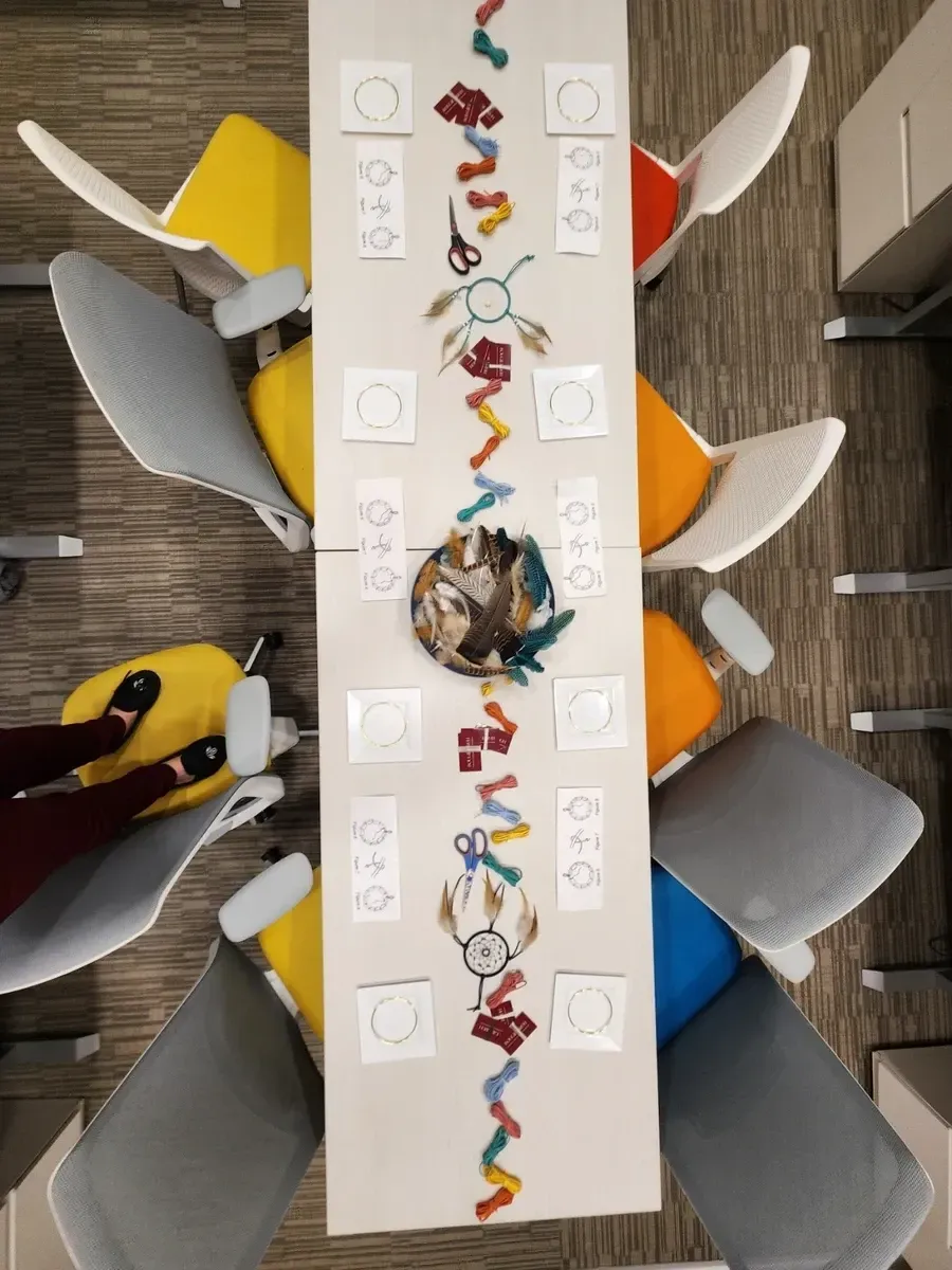 Overhead view: white table decorated with colorful art surrounded by colorful chairs.