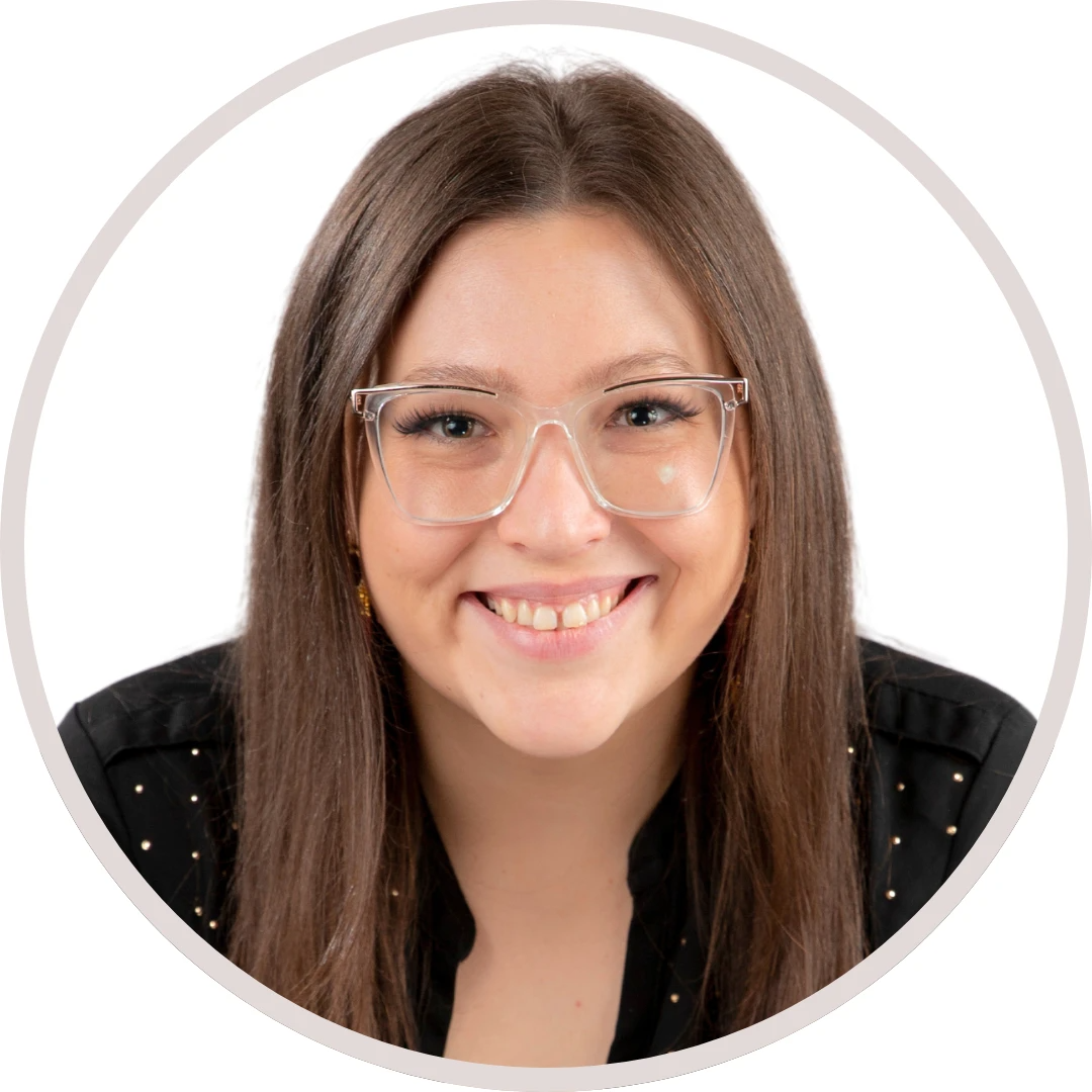 Woman with long brown hair, wearing glasses, smiling brightly.
