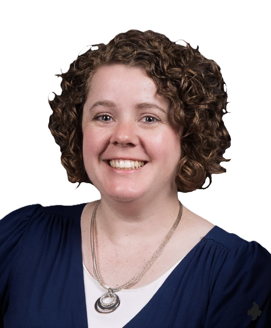 Woman with curly hair and glasses smiles at the camera in an office setting.