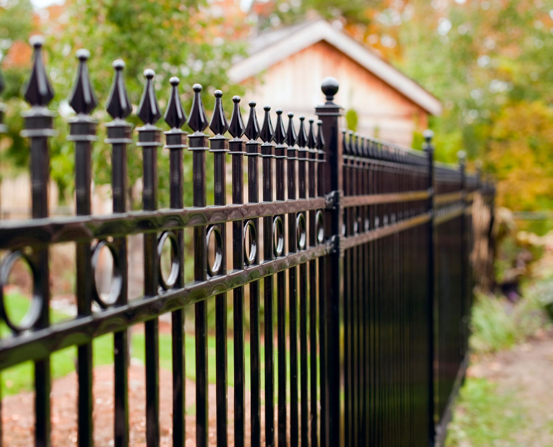 A black wrought iron fence with a house in the background.