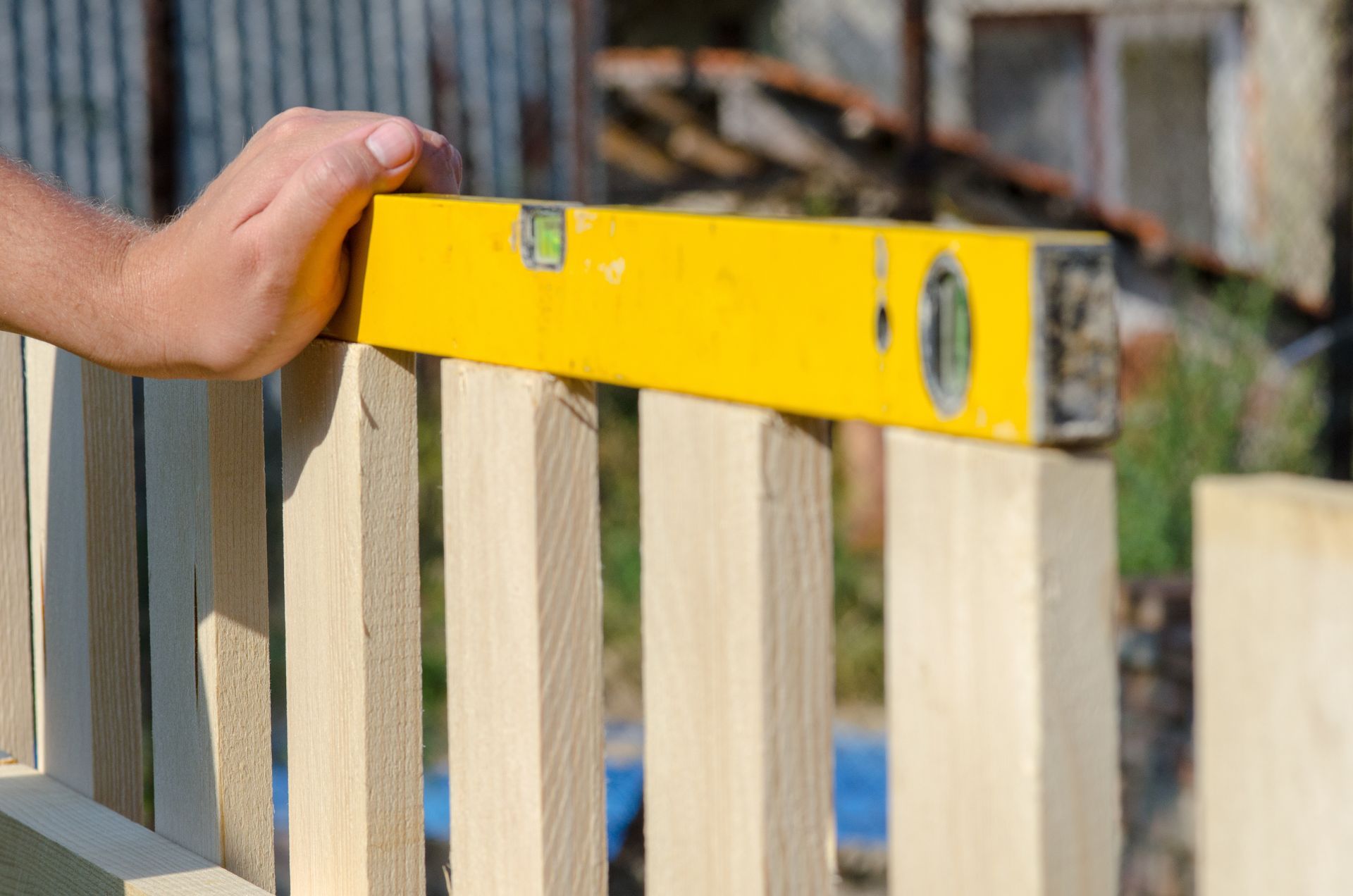 Man building a wooden fence and checking with a spirit level. Close-up of his hand and tool. Man building a wooden fence and checking with a spirit level. Close-up of his hand and tool.