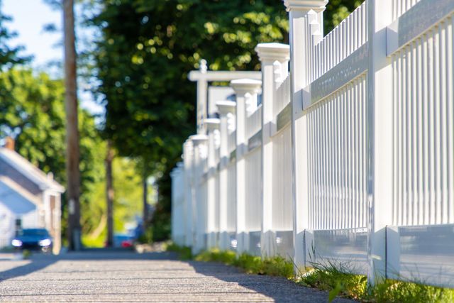 A white picket fence lining a residential sidewalk.