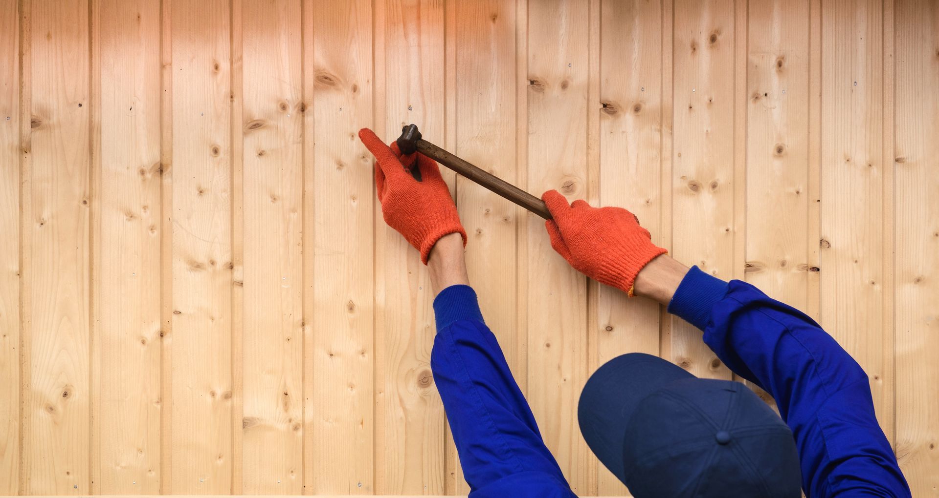 Young contractor holding a hammer building a wooden fence Young contractor holding a hammer building a wooden fence