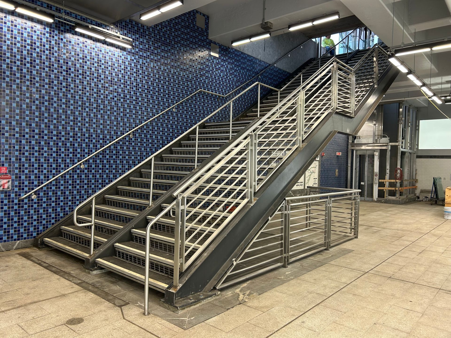 A set of stairs with a stainless steel railing in a subway station.