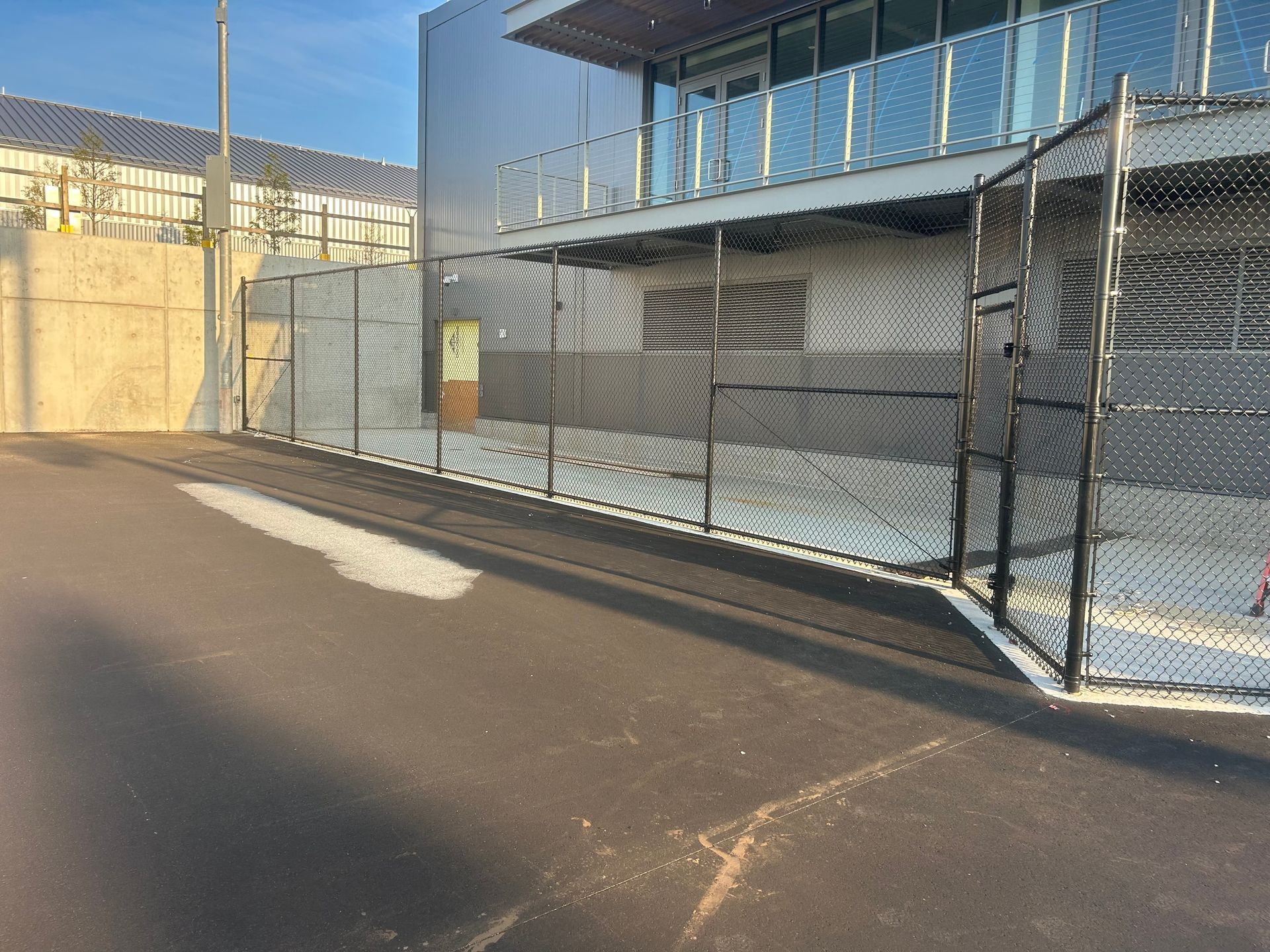 A chain link fence is surrounding a building on the side of the road.