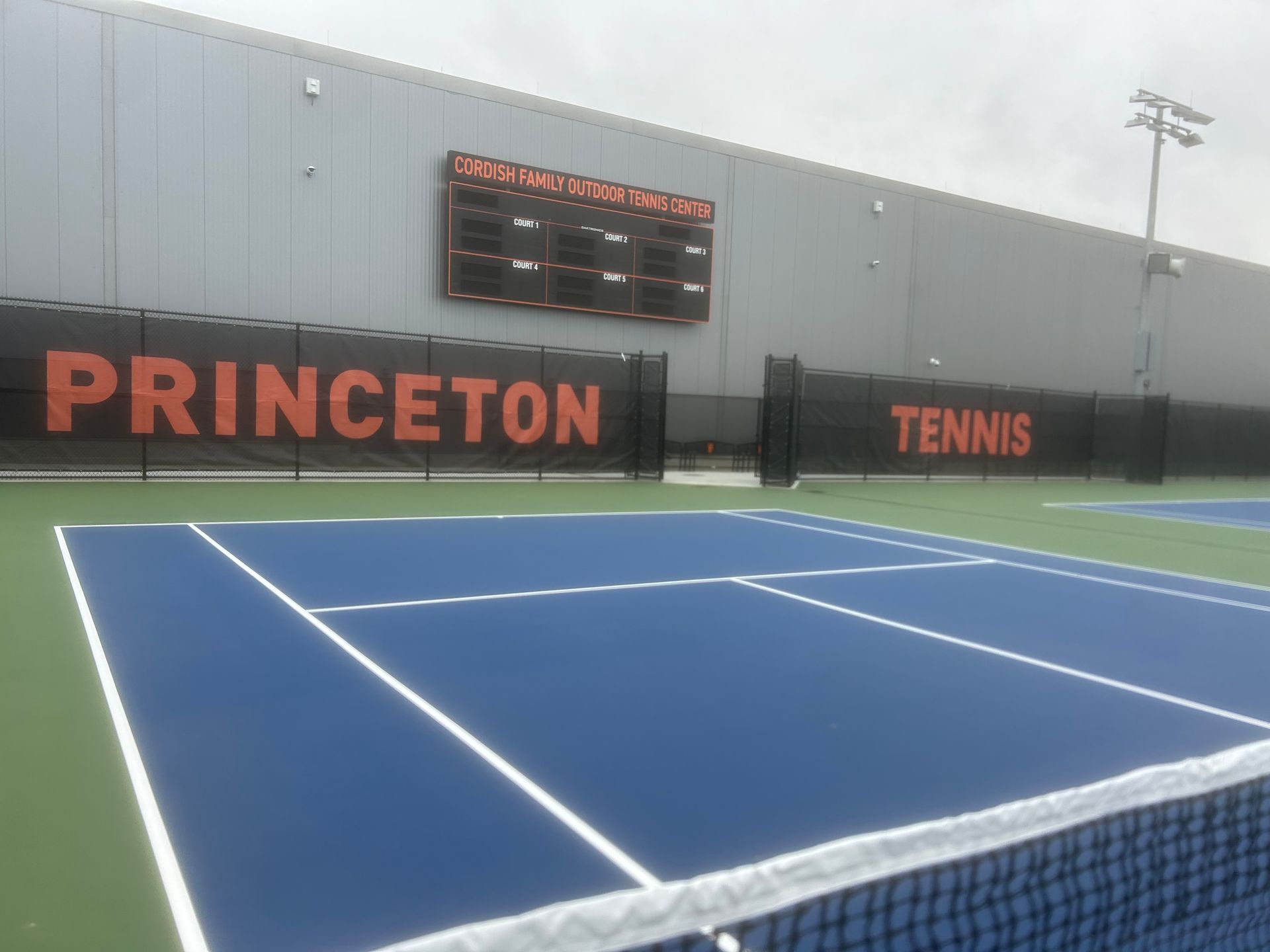 A tennis court in front of a building that says princeton tennis