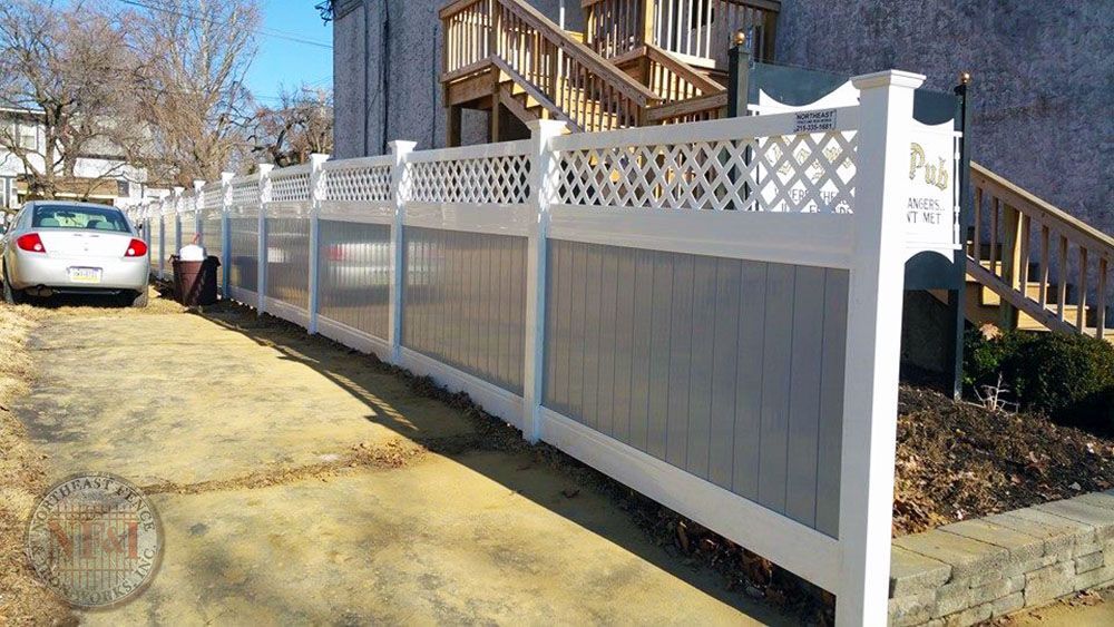A white and gray fence is in front of a house with stairs.