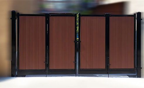 A wooden gate with a black frame is sitting on a white surface.