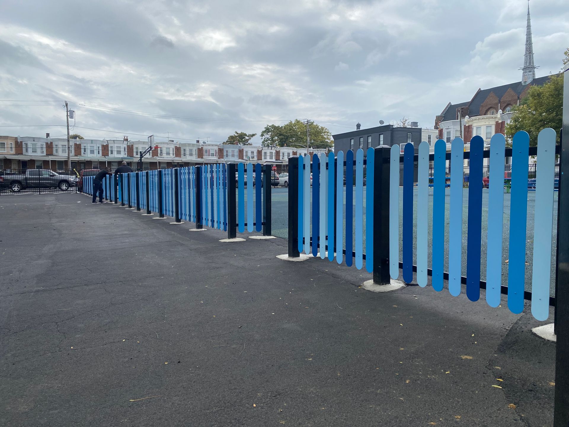 A row of blue and black picket fences in a parking lot