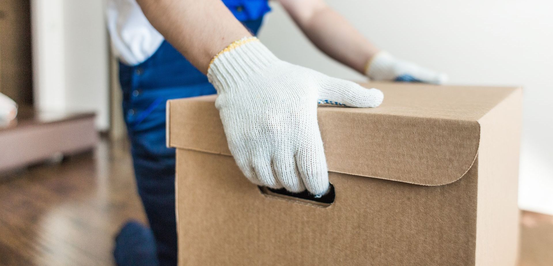 Une personne portant des gants tient une boîte en carton.