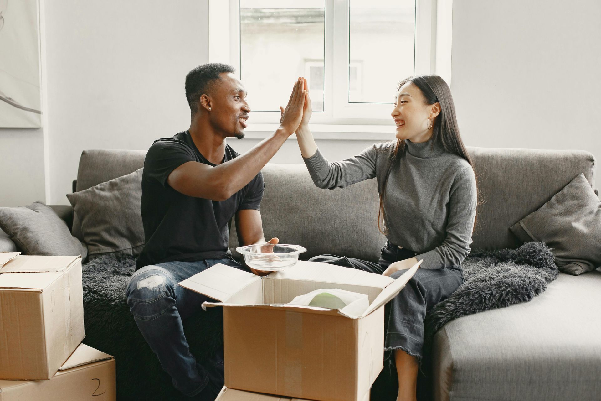 Un homme et une femme sont assis sur un canapé et se font un high five.