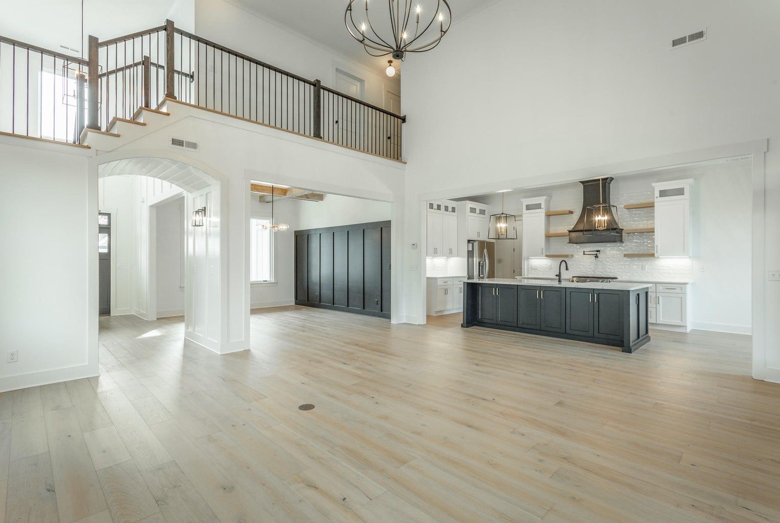 A large empty room with hardwood floors and a kitchen.