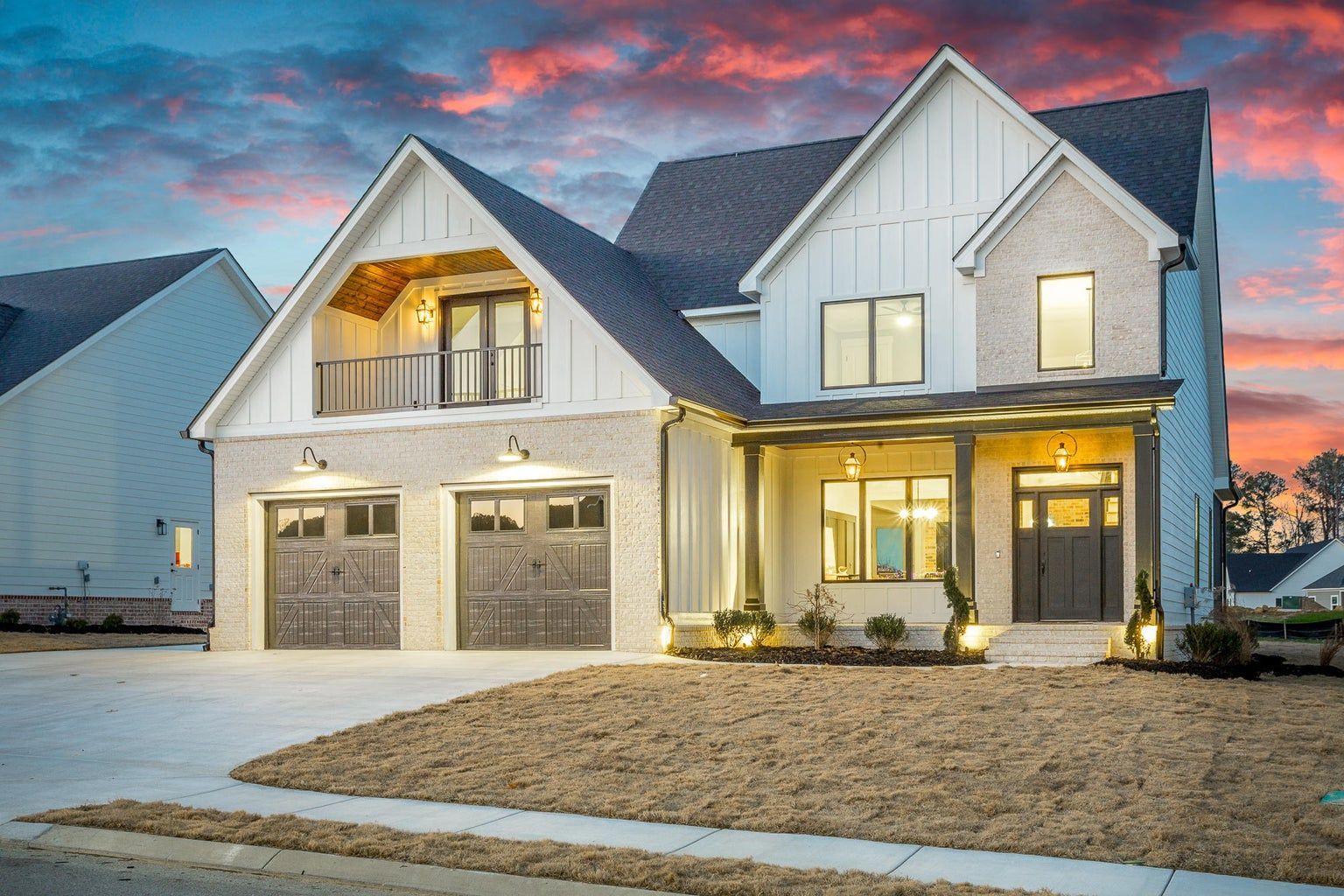A large white house with two garages is lit up at night.