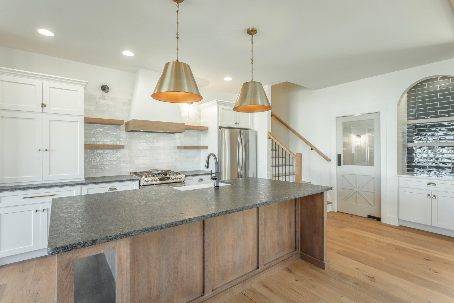 A kitchen with a large island , granite counter tops , white cabinets and hardwood floors.