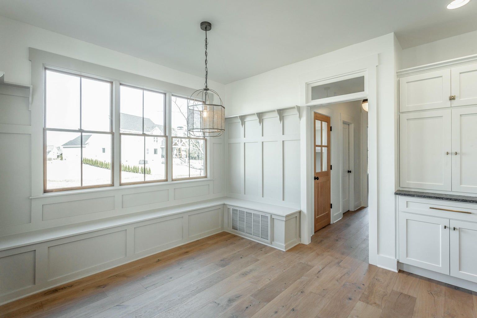 There is a bench in the corner of the room with a lot of windows.