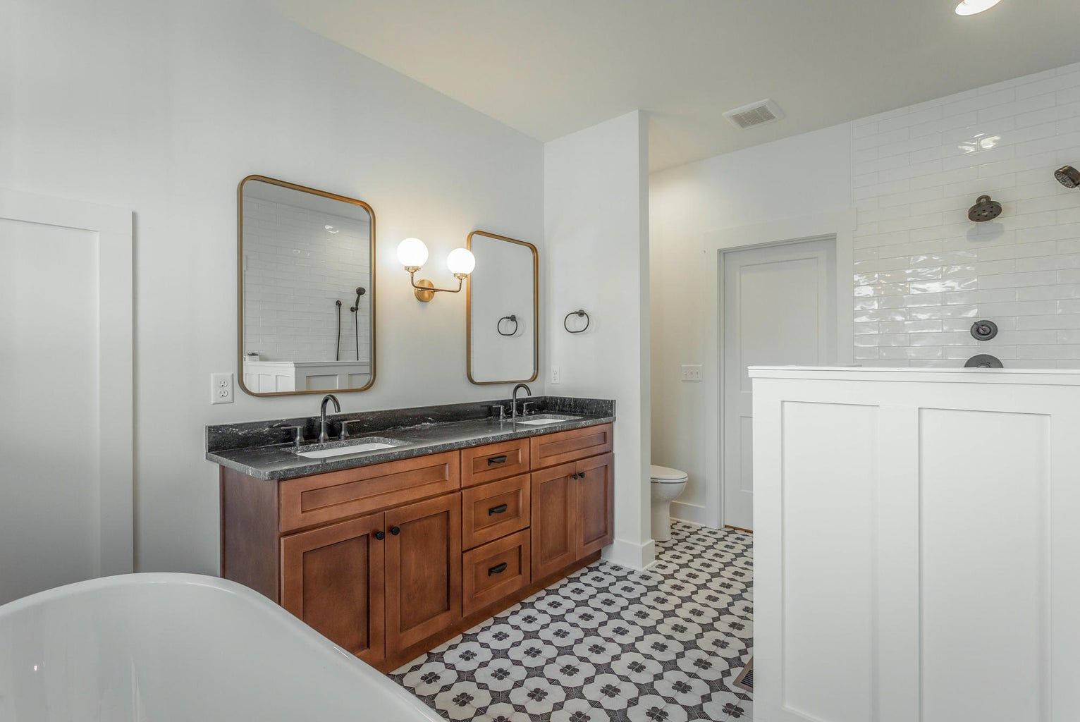 A bathroom with two sinks , two mirrors and a bathtub.