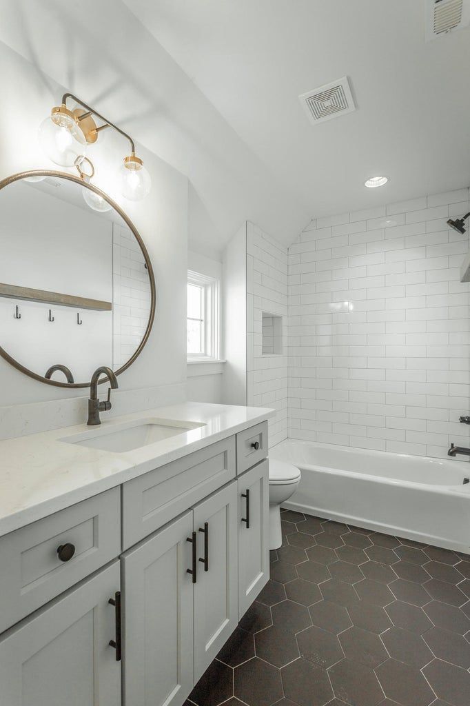 A bathroom with a sink , toilet , tub and mirror.