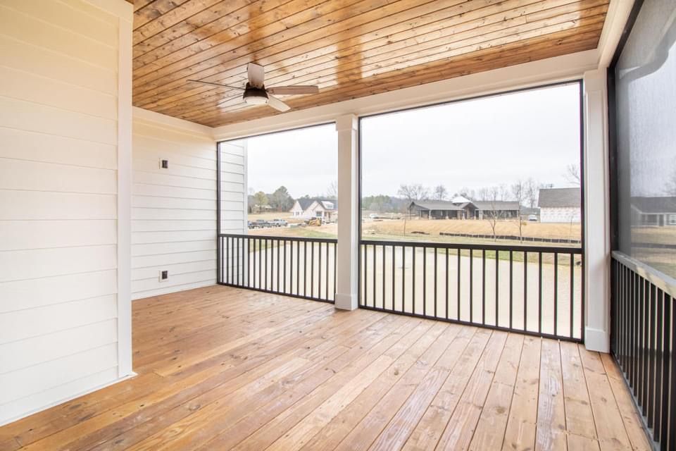 a screened in porch with wooden floors and a ceiling fan .