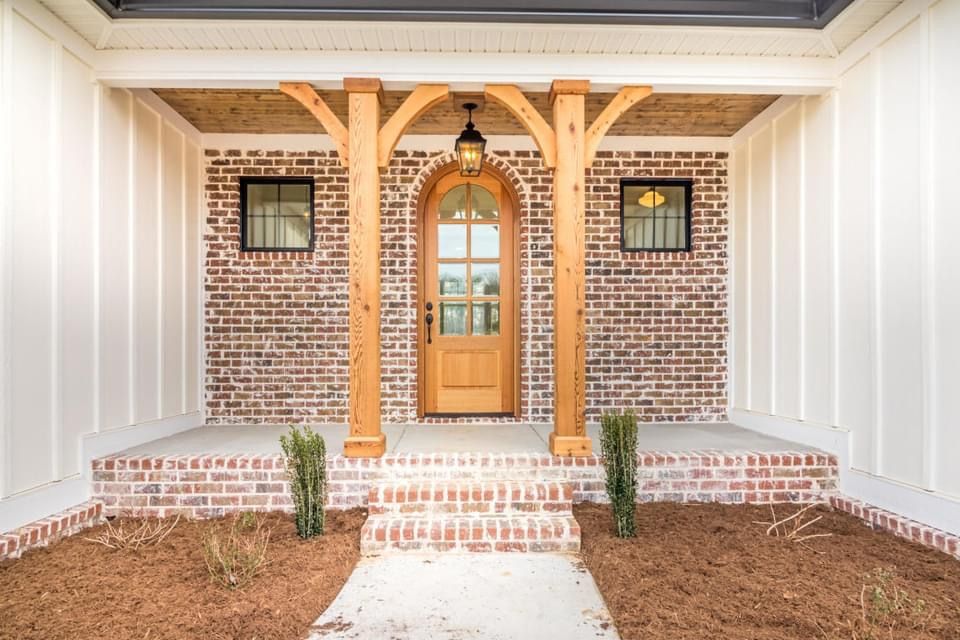 a brick house with a wooden porch and a wooden door .