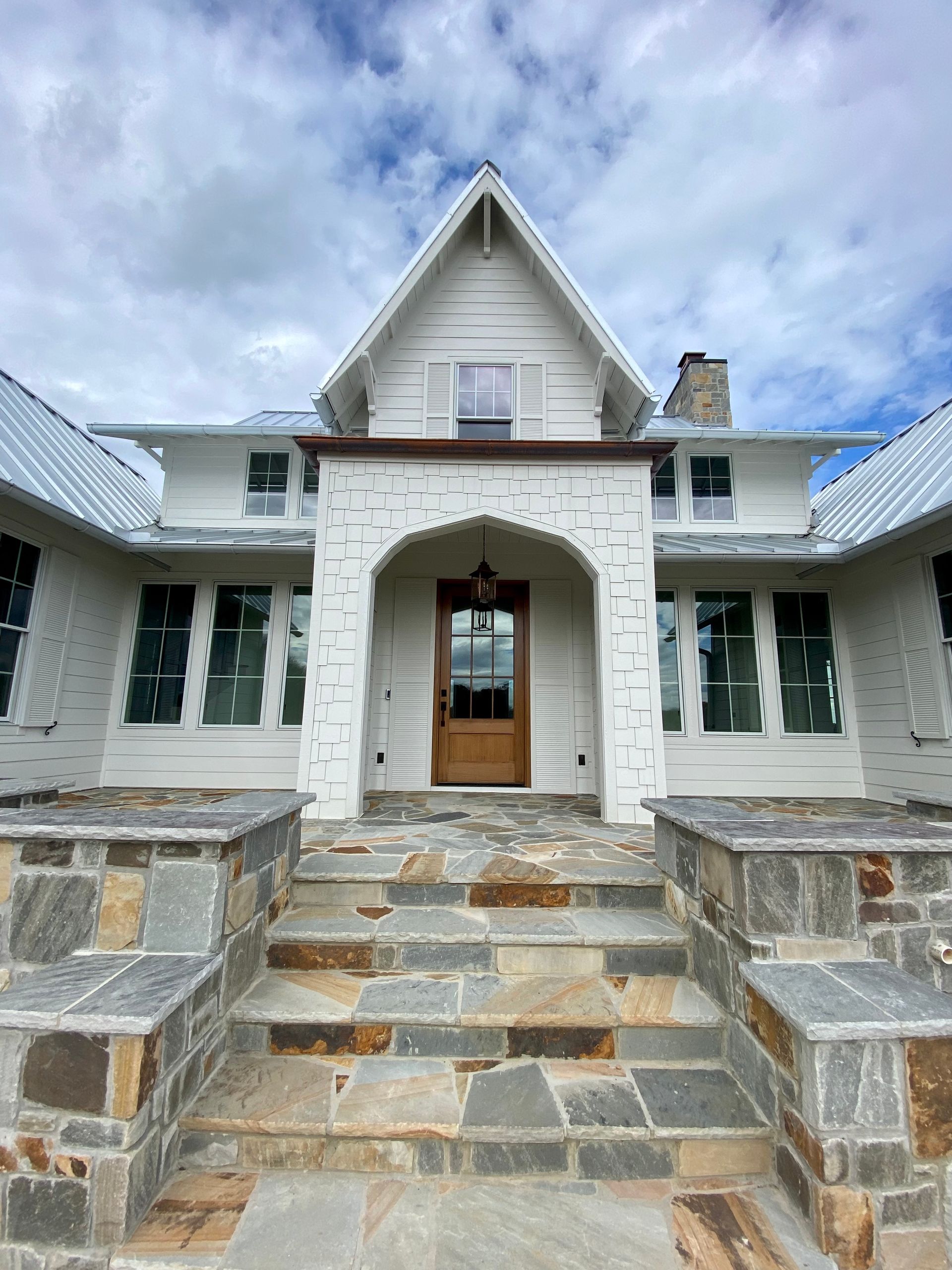 A large white house with a stone walkway leading to the front door.