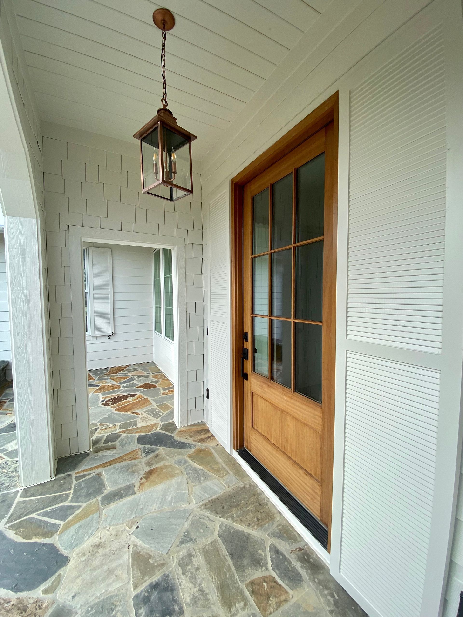 A porch with a wooden door and a lantern hanging from the ceiling.