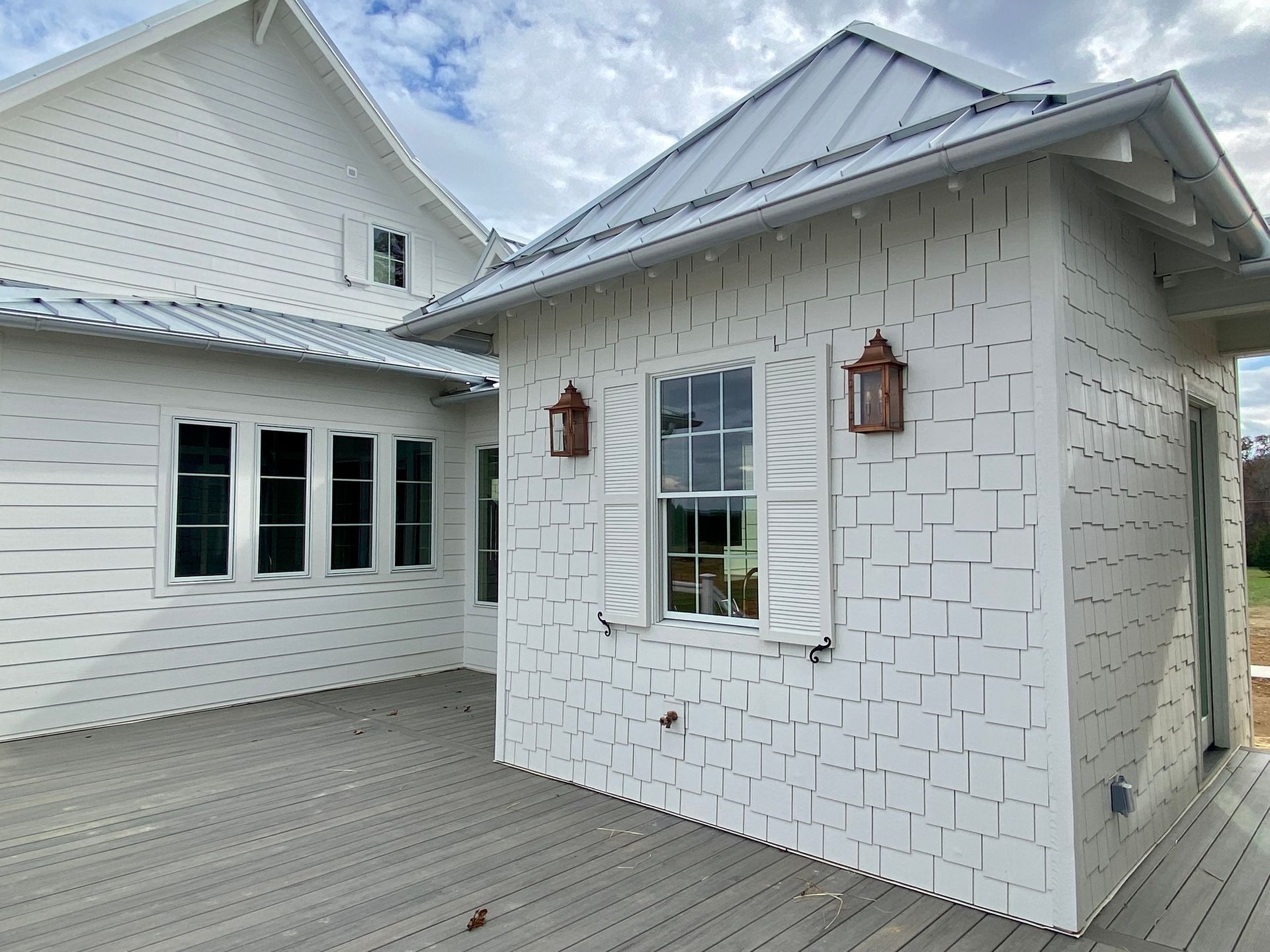 A white house with a metal roof and shutters on the windows