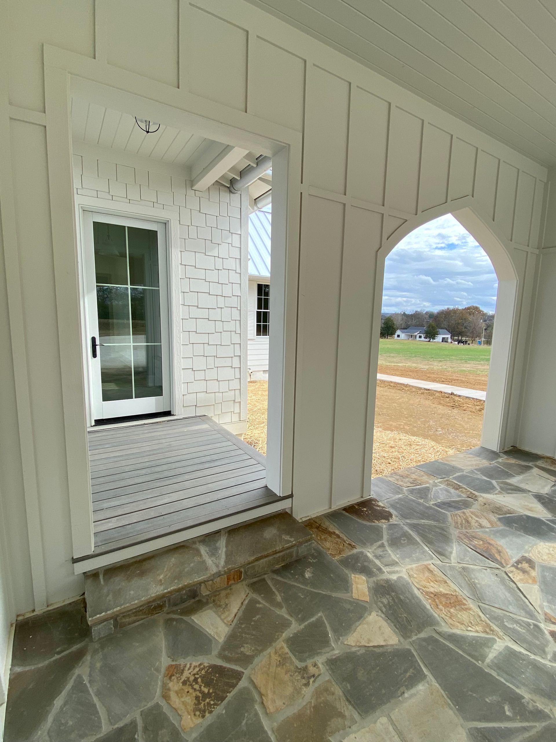 A porch with a stone floor and a white door