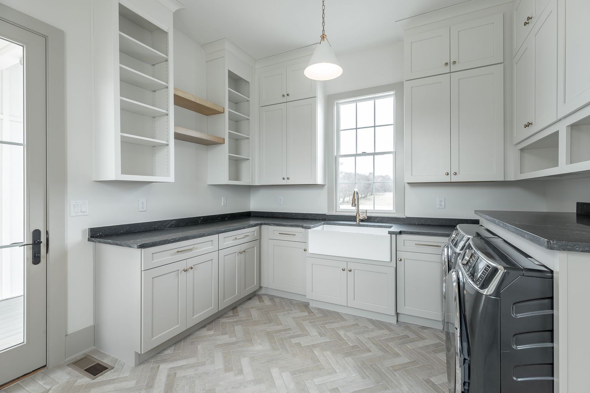 A kitchen with white cabinets , black counter tops , a stove and a sink.