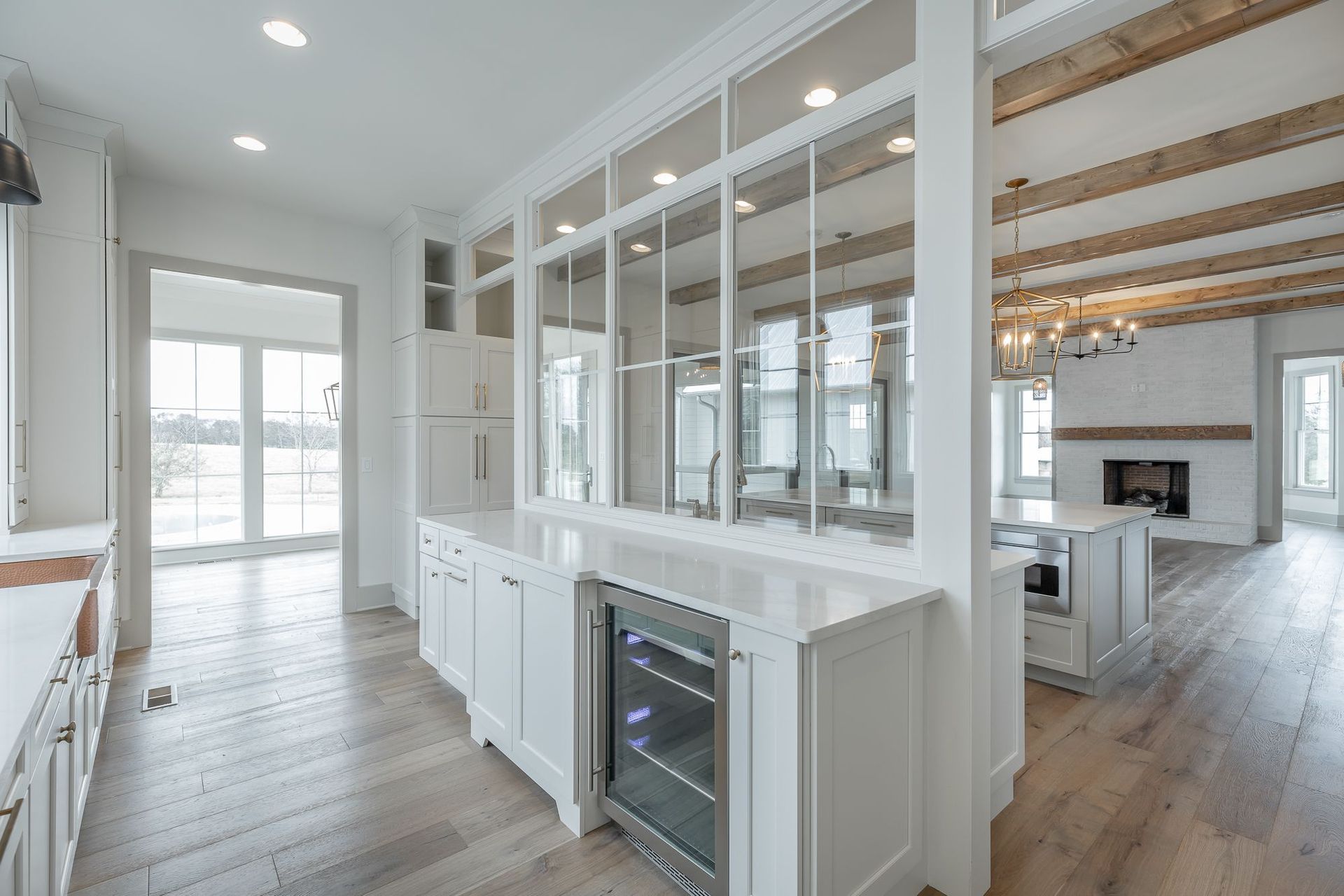 A kitchen with white cabinets , hardwood floors , and a refrigerator.