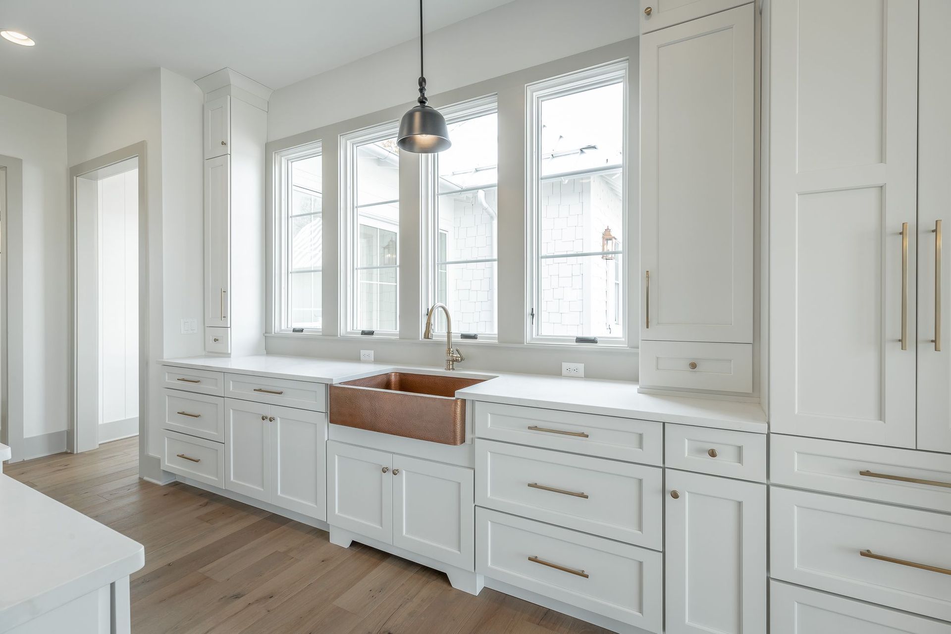 A kitchen with white cabinets and a copper sink.