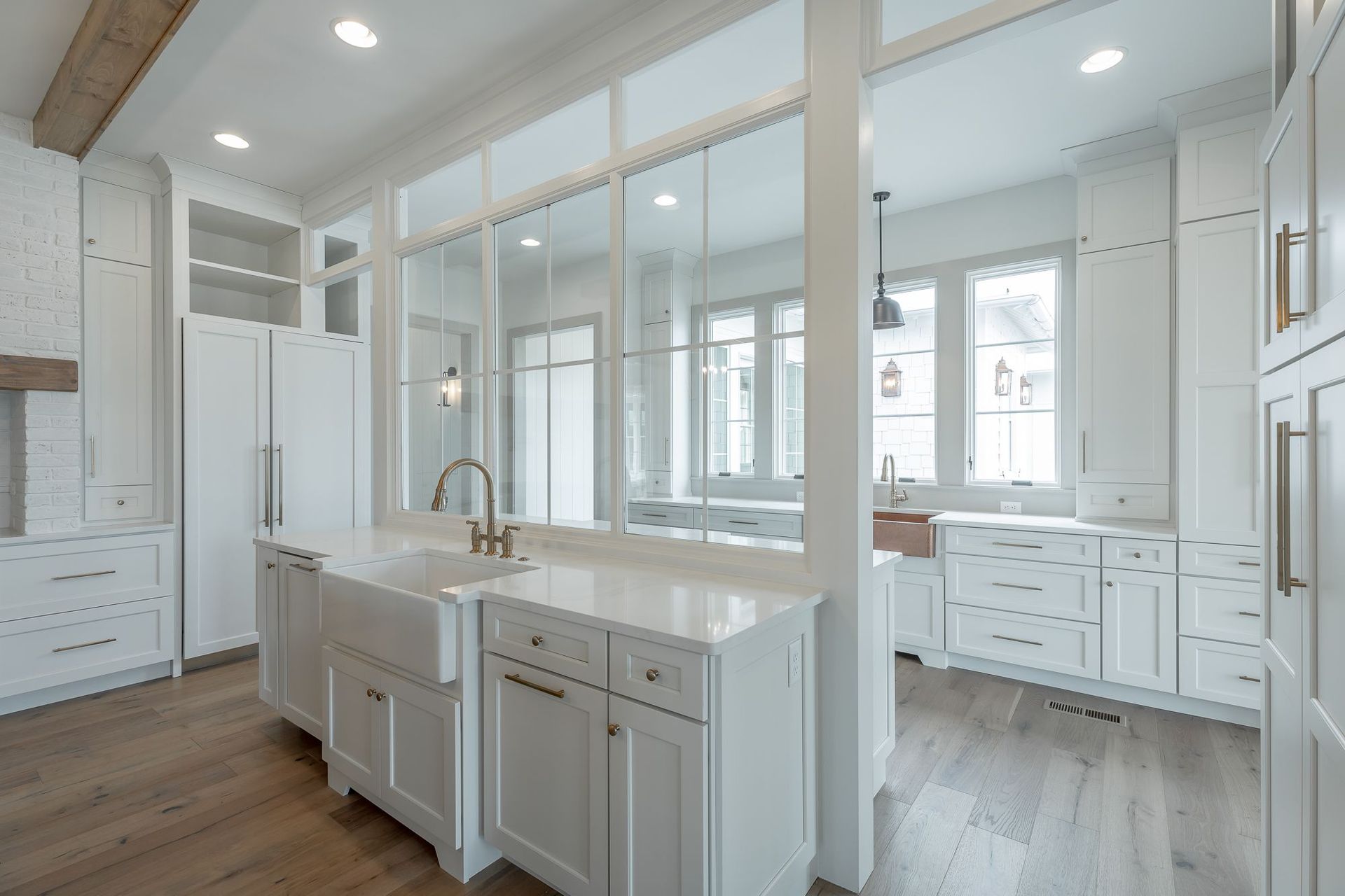 A kitchen with white cabinets , a sink , and a lot of windows.