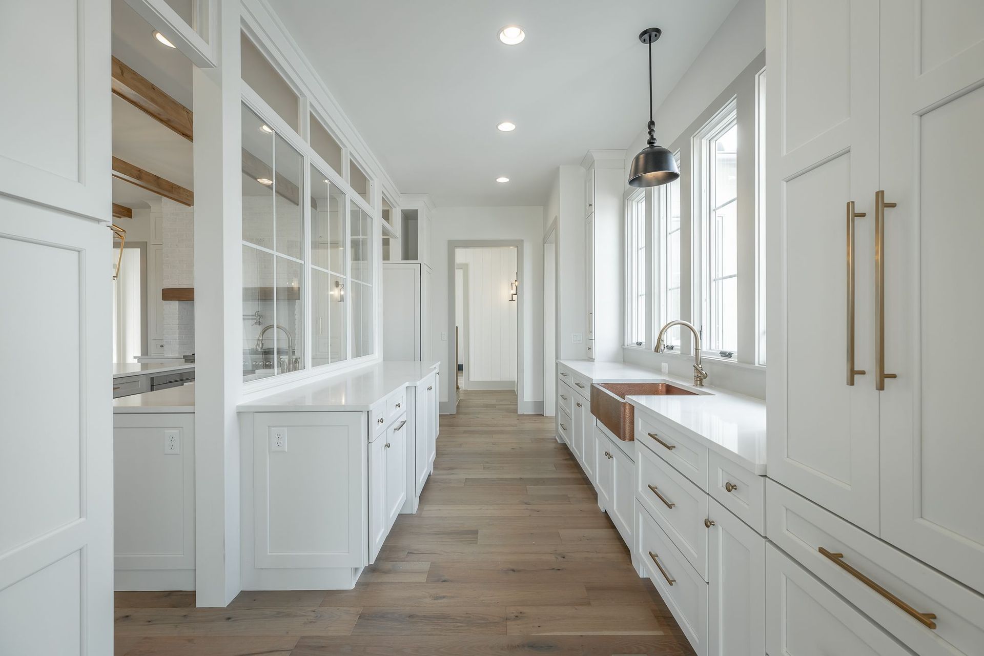 A kitchen with white cabinets and hardwood floors and a sink.