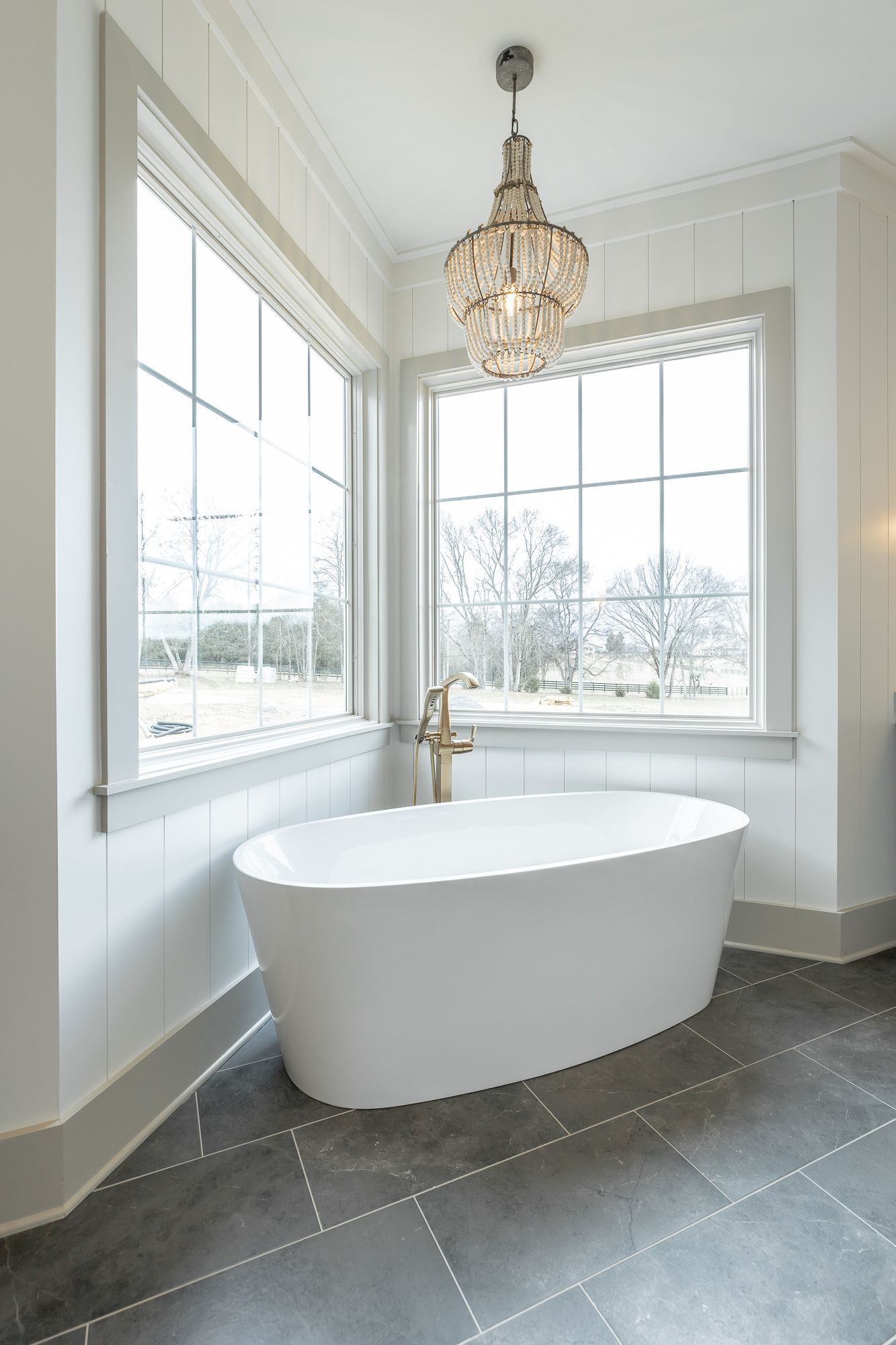 A bathroom with a bathtub and a chandelier hanging from the ceiling.