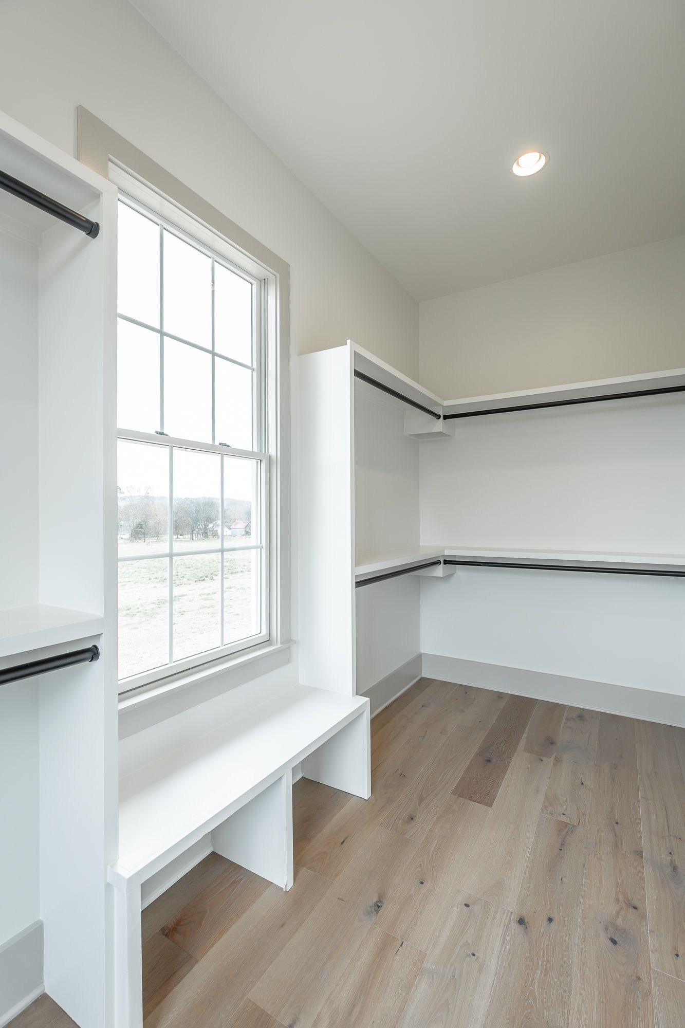 A walk in closet with a bench and a window.