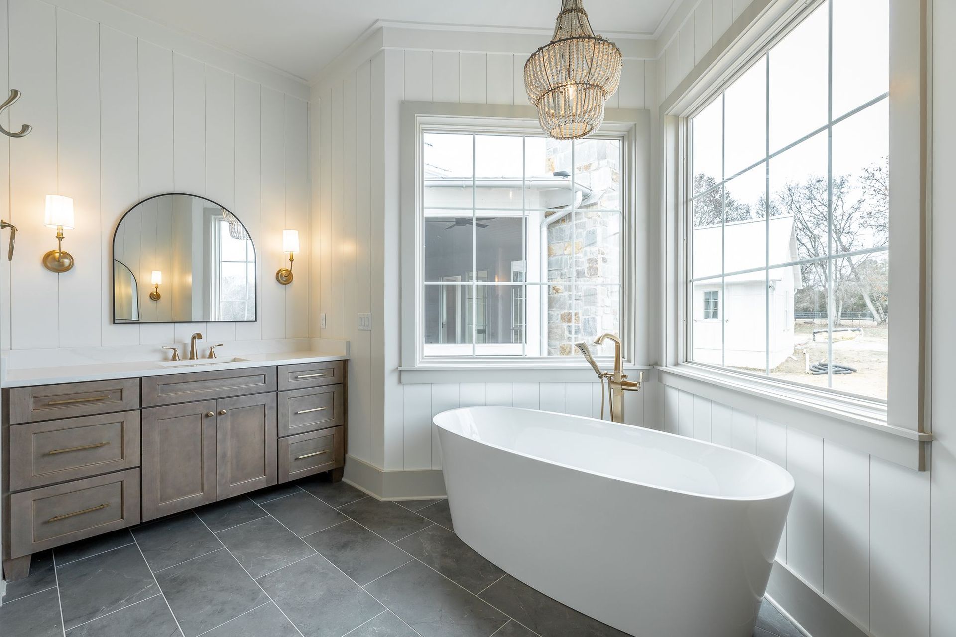 A bathroom with a tub , sink , mirror and window.