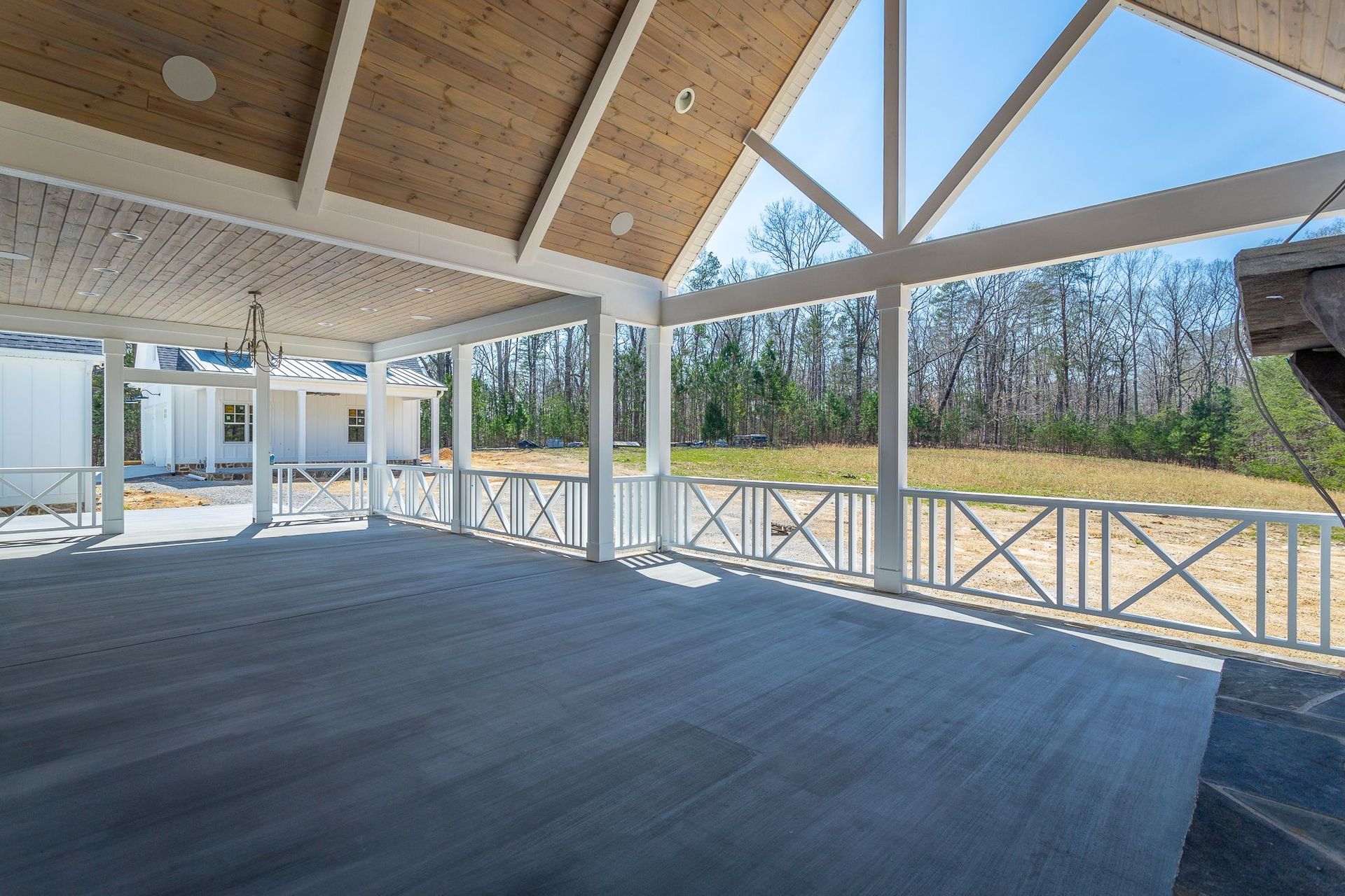 a large covered porch with a wooden deck and a white railing .