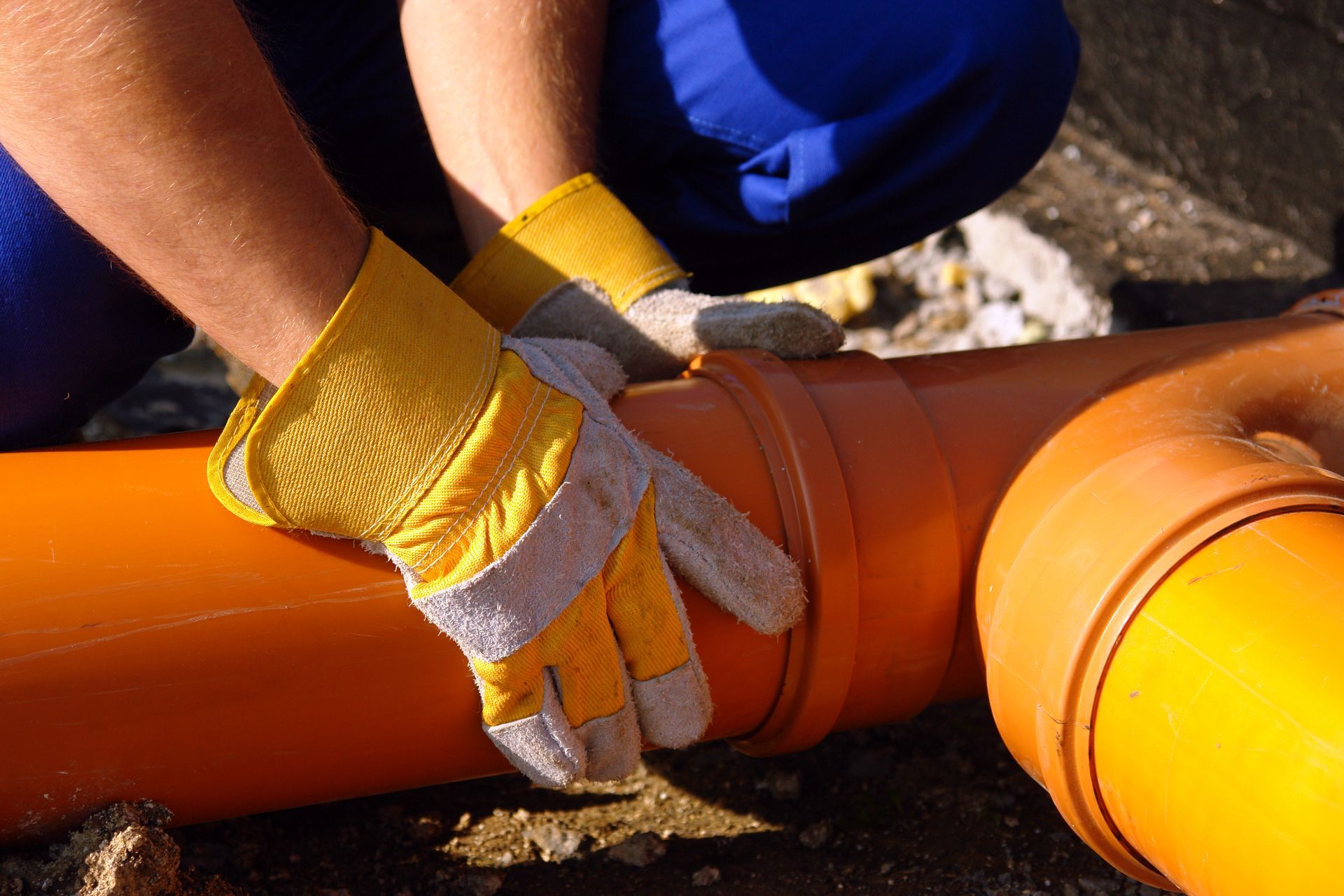 Closeup of plumber's hands assembling pvc sewage pipes.